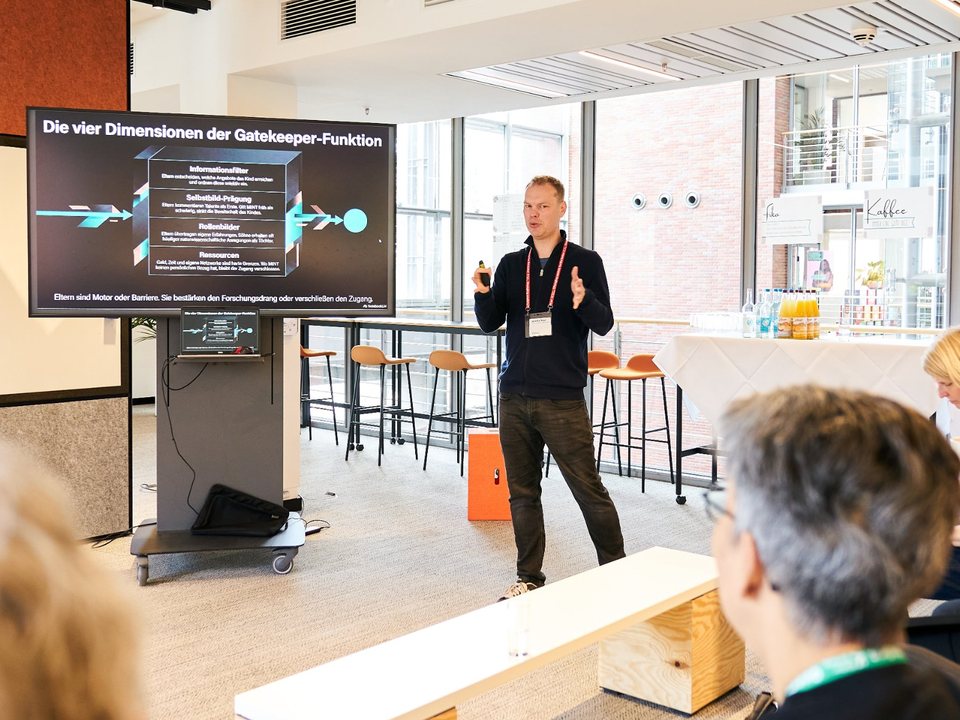 Sascha Bohn erklärt vor Publikum die vier Dimensionen der Gatekeeper-Funktion von Eltern